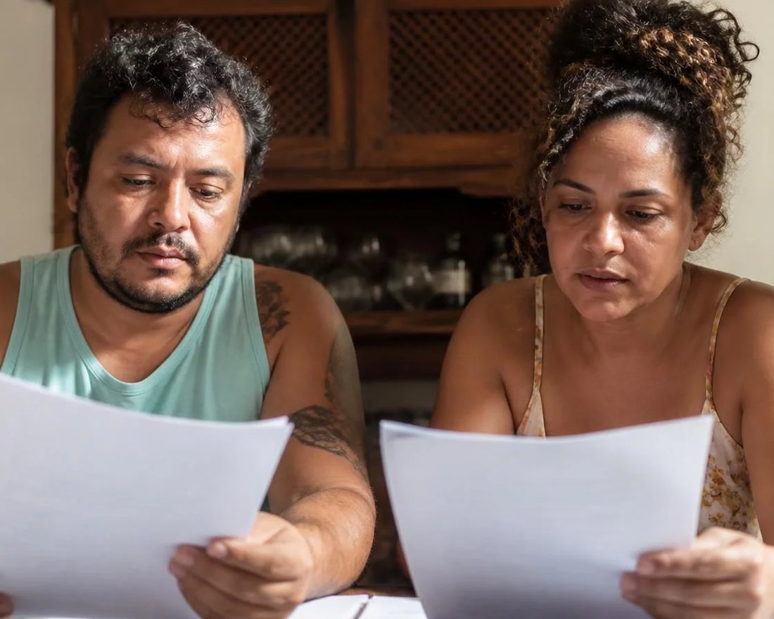 Dupla discute em pé entre as estantes de uma biblioteca, cada um sustentando o seu ponto